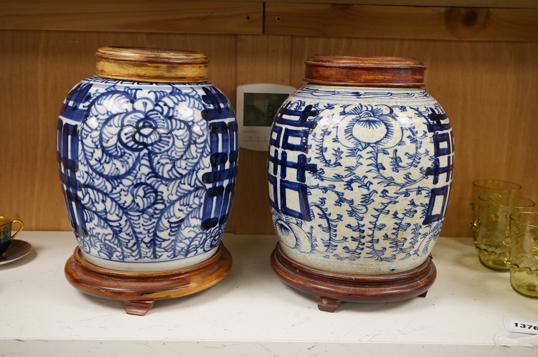 Two Chinese blue and white jars with hardwood stands and covers, 28cm high